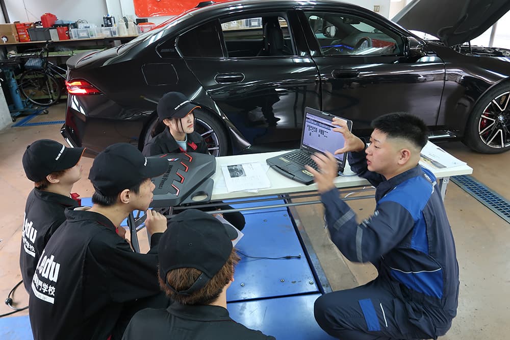 京都自動車専門学校（KCGM）と株式会社マツシマホールディングスとの企業連携セミナーで，BMW故障診断機を使い，学生に直接レクチャーする卒業生（KCGM猪熊校舎）